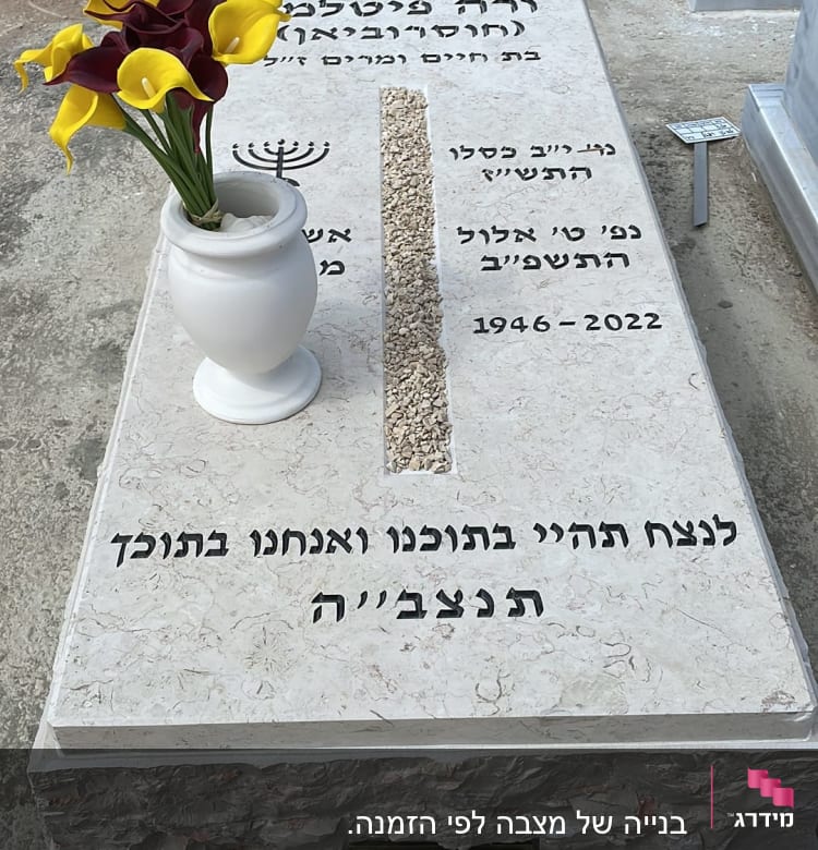 מצבה עם כיתוב בעברית ואגרטל פרחים